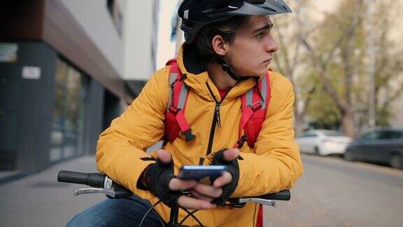 骑自行车的快递员在手机上查看顾客的地址