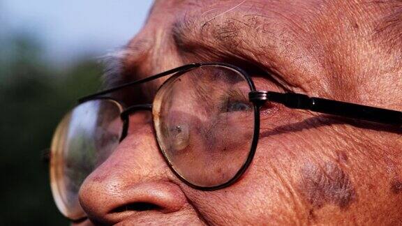 一位戴着眼镜的老人的特写脸在阳光下眺望远方眼光和老年人的观念