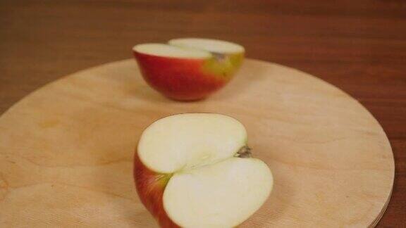一个女人用一把刀在木板上把苹果切成两半的特写