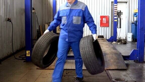 男人带着磨损的轮胎储存冬天用过的轮胎