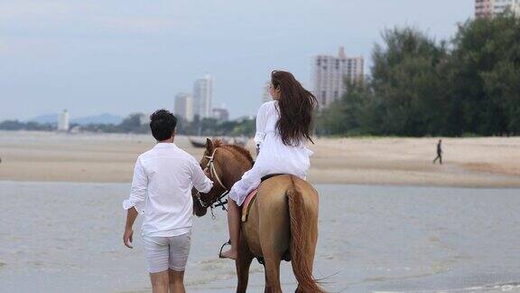 4k情侣散步享受海滩和快乐退休夫妇在热带度假和年轻女人骑在海边的马