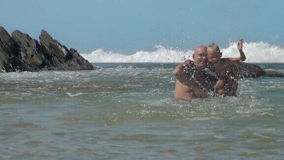 爸爸抱着儿子在温暖的海洋里泼水