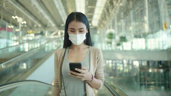 亚洲妇女在机场使用手机戴医用口罩