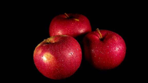 潮湿的红苹果在黑色的背景上打开