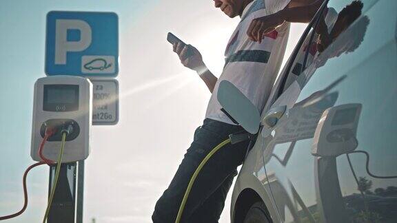 一名年轻人在停车场充电时使用智能手机