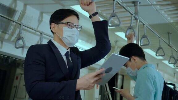 亚洲上班族乘坐地铁时戴口罩预防新冠肺炎在新冠肺炎疫情情况下外出工作时要注意保持社交距离是为了安全