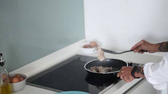 高角度亚洲华人高级男子在厨房的炉灶上烹饪培根在准备早餐