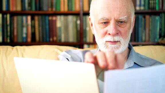 英俊的老年人在家里用笔记本电脑工作退休后从事远程自由职业