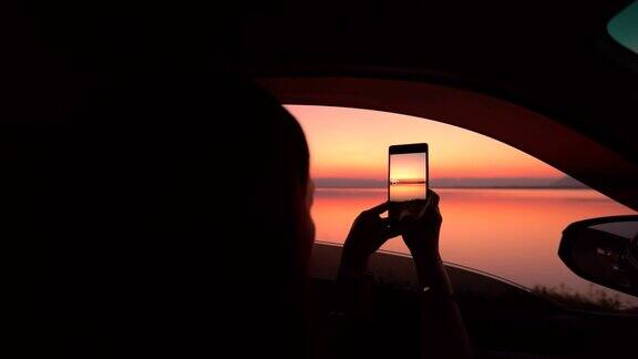 剪影女子在车里欣赏湖上的日落慢镜头