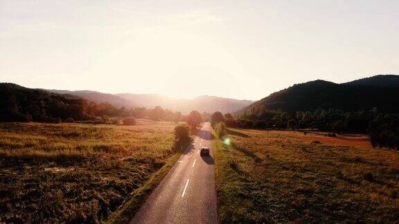 汽车行驶在空旷的乡间小路上进入了金色的夏日夕阳