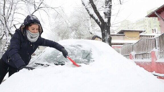 年轻女子在掸掉车上的雪
