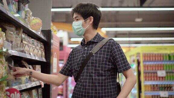 年轻男子戴着防护口罩在超市购物