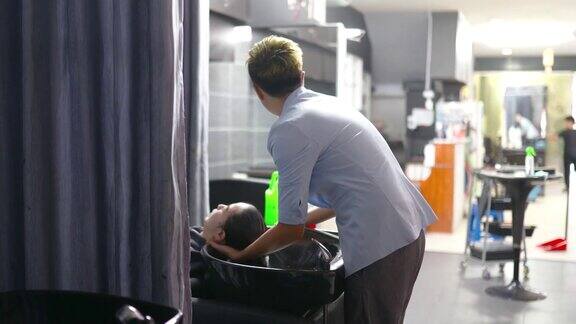 亚洲华人发型师在发廊为顾客洗头