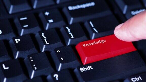 男性手指按下电脑键盘上红色的“知识”按钮