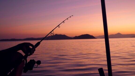 日出时分在宁静的大海边渔夫拿着钓竿的剪影