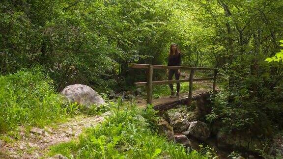 一位年轻的女子正穿过山间小溪上的一座小木桥