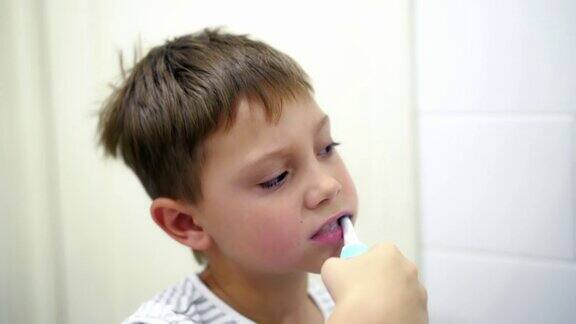 可爱的白人男孩在浴室用电刷刷牙的特写镜头