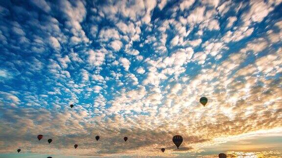 日出时热气球飞过卡帕多西亚山谷空中无人机的视角引人注目的晨光
