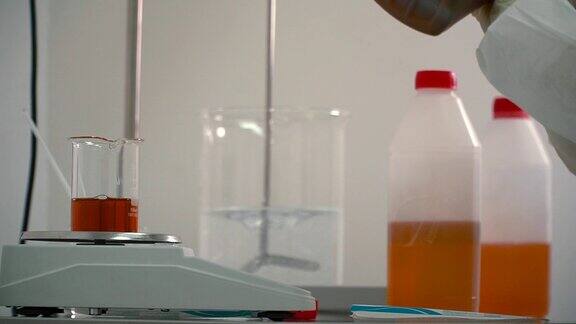 药剂师用移液管将液体从瓶子中加入到电子秤上的烧瓶中