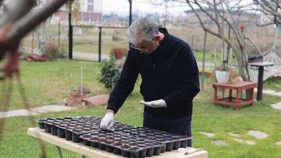 中年男子播种、锄地、手栽绿苗、社区园艺、城市园艺、城市农业、园地、城市农业、可持续园林、滴灌