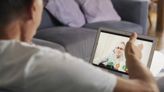 白人老人坐在沙发上通过视频通话用红色氦相机在8K拍摄