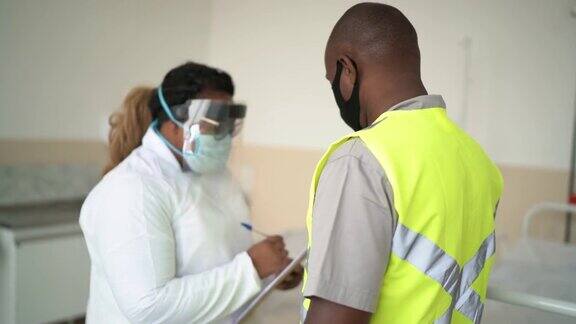 医生向工作病人询问问题并在医院填写表格-戴口罩