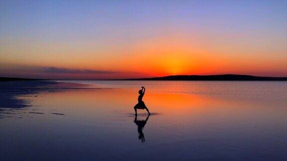 年轻的芭蕾舞演员日落时在湖面上跳舞