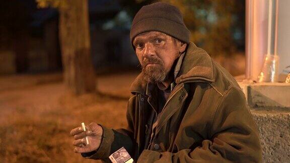 一个无家可归的人在秋天的夜晚在街上吃饭