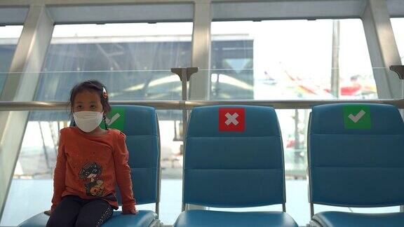 可爱的人戴着防护口罩坐在蓝色的椅子上在机场保持社交距离