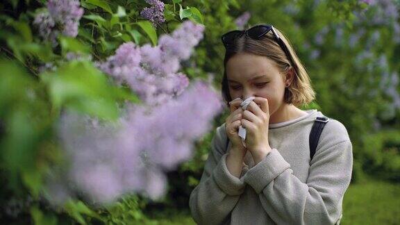 女孩有过敏喷嚏和清洁鼻子在公园附近盛开的鲜花在春天