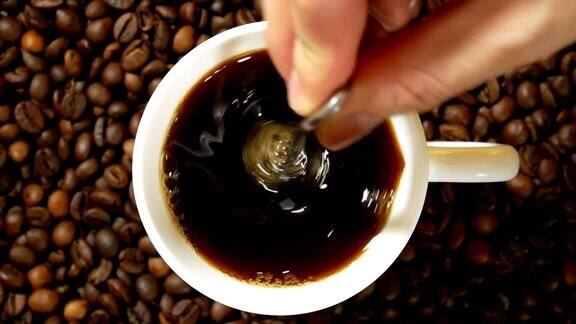将咖啡倒入白色的杯子中搅拌然后用手挑出一个放在烘培咖啡豆堆上的杯子