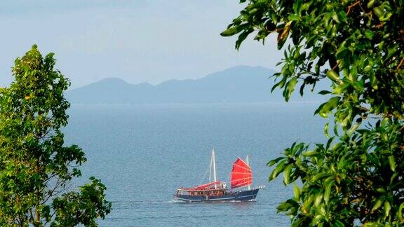 日落时分一艘中国传统的红帆船在海上漂浮