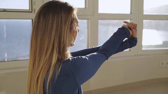 年轻女子在窗边做手臂运动