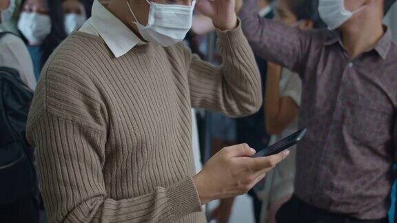 商人在地铁乘坐期间戴着保护面罩使用智能手机特写