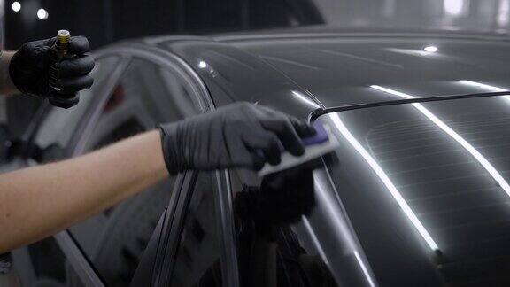 师傅正在用海绵手里拿着瓶子用纳米陶瓷液体擦拭汽车表面