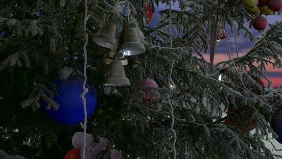 一棵装饰好的圣诞树在夜晚闪烁着花环灯上面挂着铃铛和一个蓝色的大球特写镜头模糊的背景