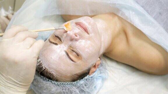 女人得到脸部脱皮面膜在水疗美容沙龙