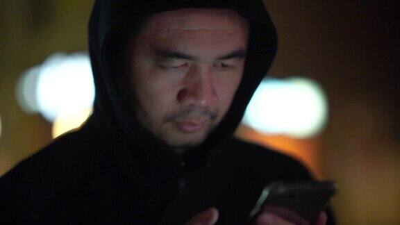 亚洲男子在城市街道上使用智能手机夜景
