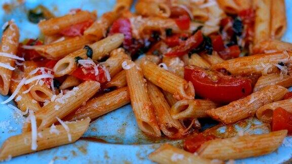 意大利面配上美味的番茄酱肉帕尔马干酪和西红柿用叉子和蓝色的盘子吃意大利面