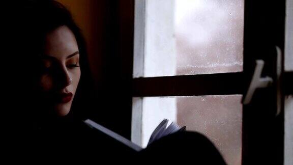 年轻女子在窗边看书