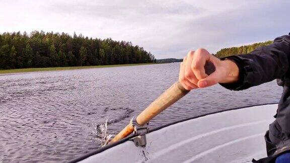 一个年轻人在湖上的一条小船上漂浮着行桨