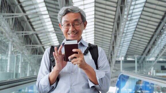 亚洲资深男子正看着他的手机屏幕他正站在机场旅行旅行全球、生活方式、假期、技术概念在机场
