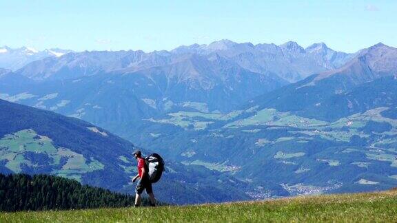 背着背包的滑翔伞在山顶上行走