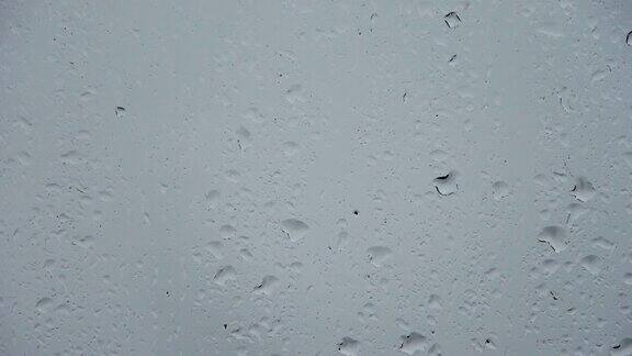 在一个近距离的视图中雨滴沿着窗户流下