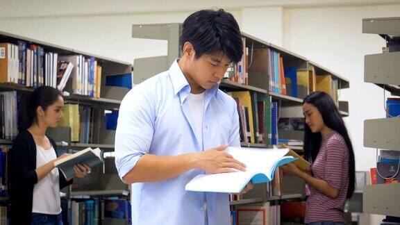 年轻快乐的亚洲学生男人在大学图书馆看书和她的同学在背景教育和学校的理念