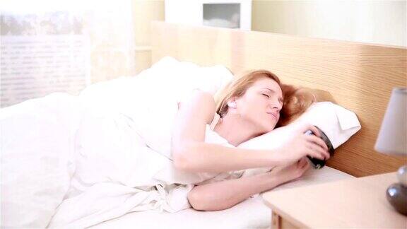 年轻的红头发女人早上不想起床把闹钟铃声藏在他的枕头下