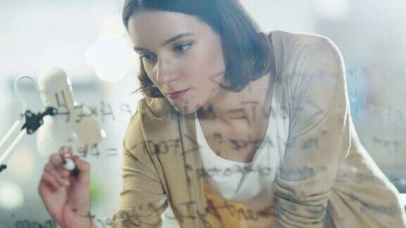 一个美丽而富有创造力的女人在玻璃白板上写公式的特写
