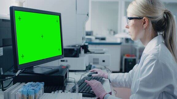 女研究科学家坐在他的工作场所在实验室使用绿色模拟屏幕个人电脑背景遗传学药学研究中心