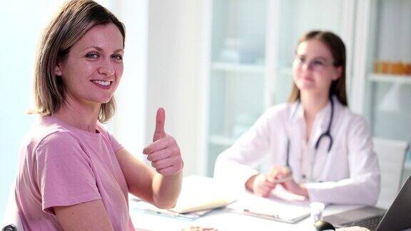 美丽快乐的女病人在诊所医生预约时竖起大拇指