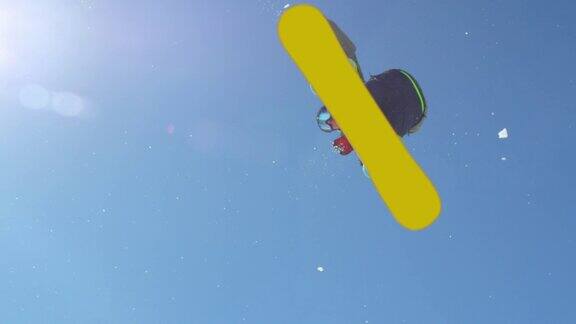 慢动作:滑雪板跳过踢球在阳光灿烂的雪园飞过太阳